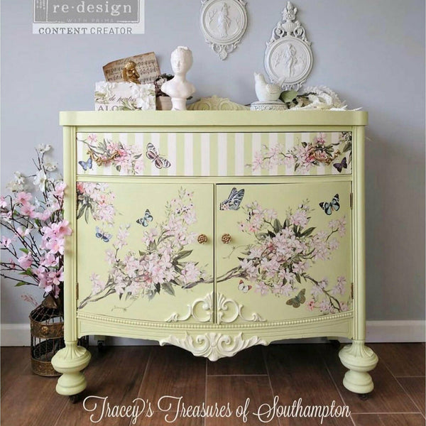 Yellow painted dresser with Blossom Botanical transfer over the front. Pink blossoms on branches and blue butterflies. A logo in the top left reading: Redesign with Prima content creator. White bottom text reading; Tracey's Treasures of Southhampton.