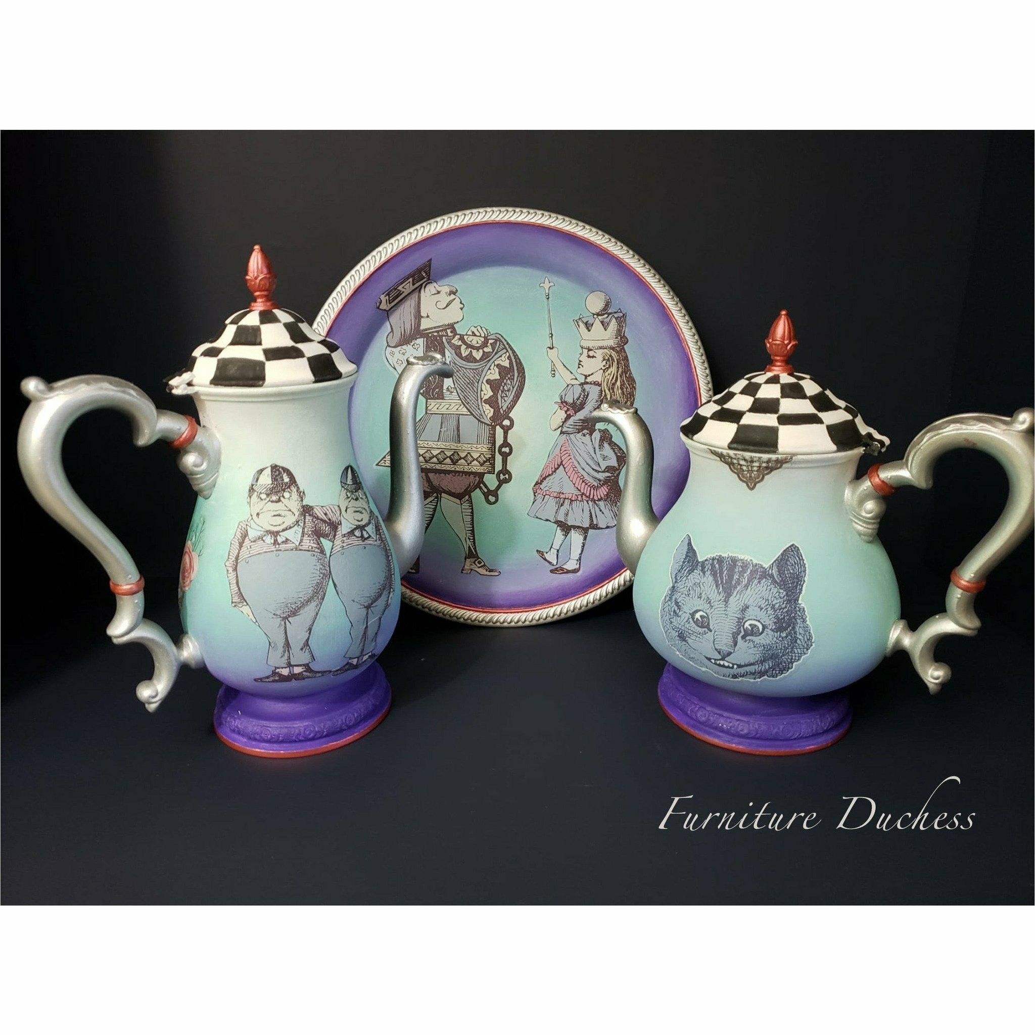 A teapot set on a black background including: plates and teapots. On the plate is Alice and Knave of hearts. On the teapot to the left is Tweedledum. On the teapot to the right is Cheshire cat. On the bottom right is a logo that reads: Furniture Duchess.