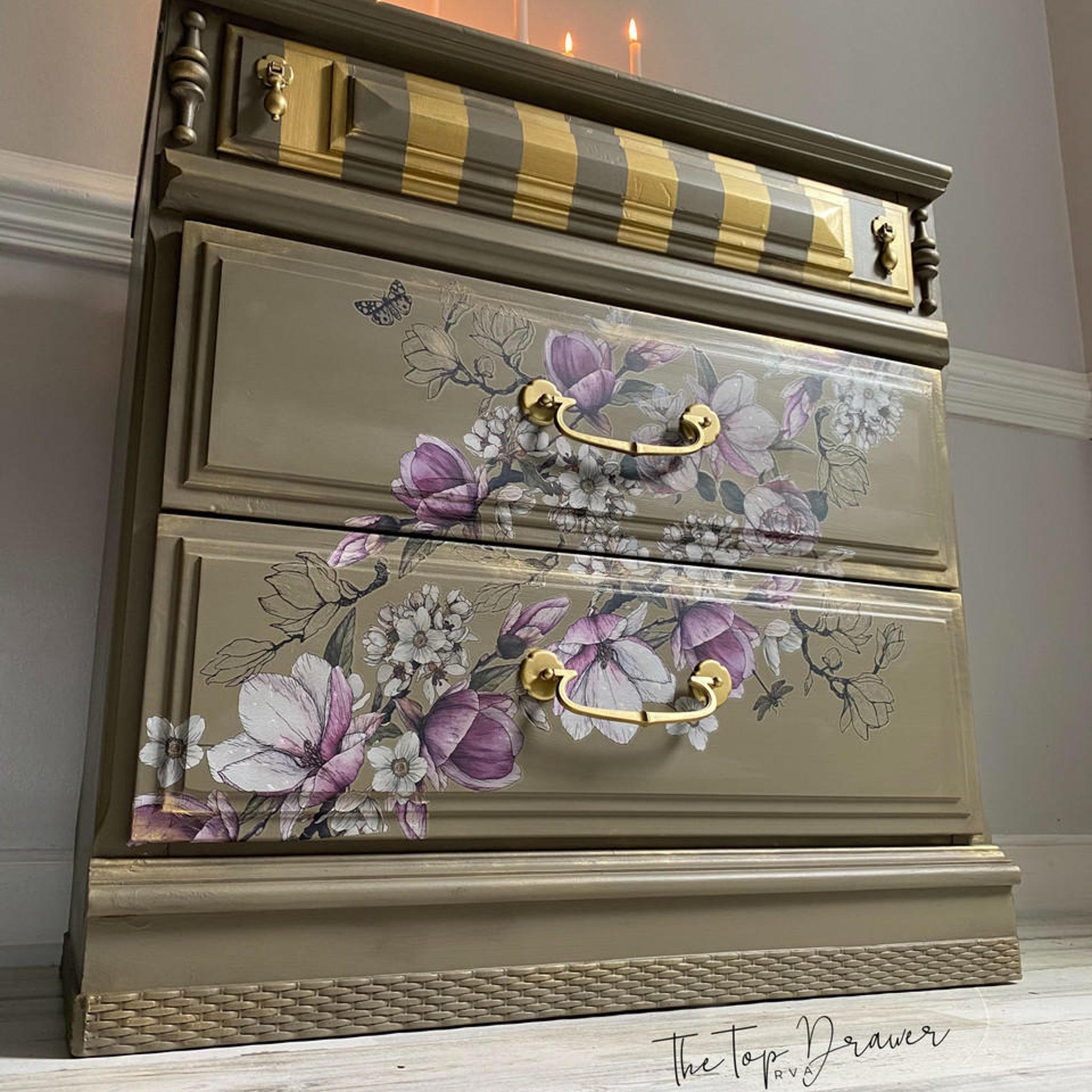 A vintage 3-drawer nightstand refurbished by The Top Drawer is painted a sage brown with gold accents and features the Buds and Branches transfer on its 2 bottom drawers.