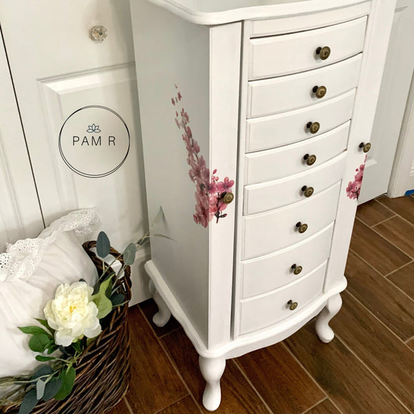 A standing jewelry cabinet refurbished by Pam R is painted white and features the Cherry Blossom transfer on the side doors.