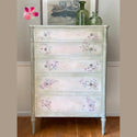 A tall 5-drawer dresser that's painted a green tinted white features the Cherry Blossom transfer on its drawers.