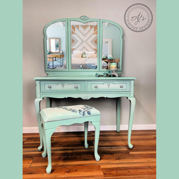 A vintage vanity desk and sitting stool refurbished by Aj's Vintage Designs is painted sea foam green and features the Cotton and Eucalyptus transfer on the stool.