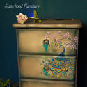 A vintage tall chest dresser refurbished by Sisterhood Furniture is painted a light sand brown and features the Retro Peacock transfer on the drawers.