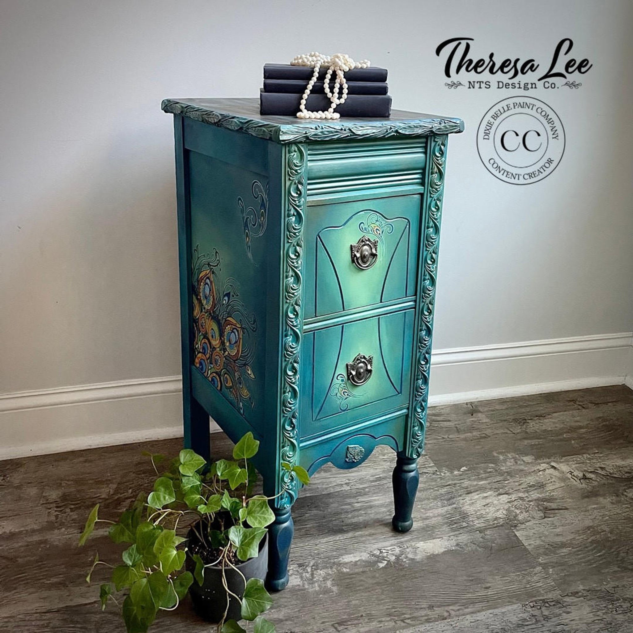 A vintage 2-drawers side table refurbished by Theresa Lee NTS Design Company, a Dixie Belle Paint Company Content Creator, is painted a blend of teal and light green and features the Retro Peacock transfer on the side. 