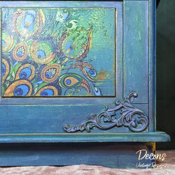 A close up a vintage wood storage chest refurbished by Decoris Vintage Designs, a Dixie Belle Paint Company Brand Ambassador, is painted a distressed blue and green and features the Retro Peacock transfer on the front of it.