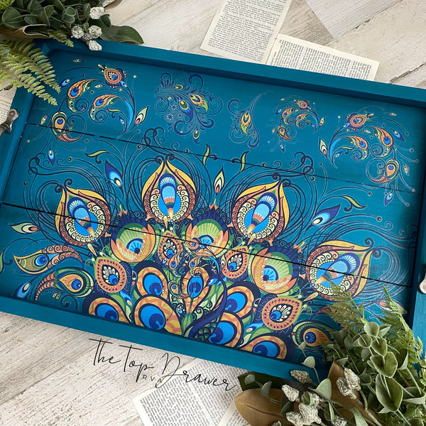 A vintage wood serving tray refurbished by The Top Drawer, a Dixie Belle Paint Company Brand Ambassador, is painted a blend of blues and green and features the Retro Peacock transfer.