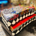 A vintage small jewelry box refurbished by Perception an Eye for Treasure Furniture Restoration Boutique is painted black & white harlequin diamonds and features the Whimsical Wonderland Transfer on the top.