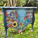 A vintage 2-drawer nightstand refurbished by TLC Vintages is painted a blend of dark and light blue and features the Whimsical Wonderland Transfer on the front.