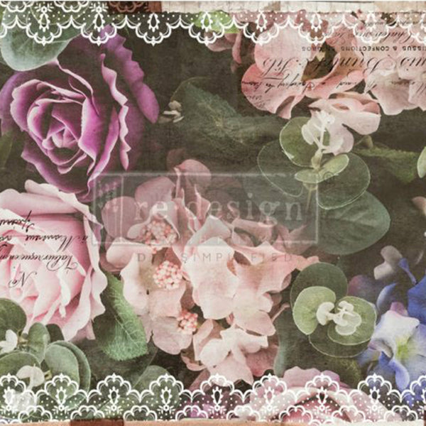 This decoupage paper by ReDesign with Prima has large pastel colored roses and flowers against a dark green background of large leaves. The edges of the paper is adorned with white lace. Some black handwriting throughout.