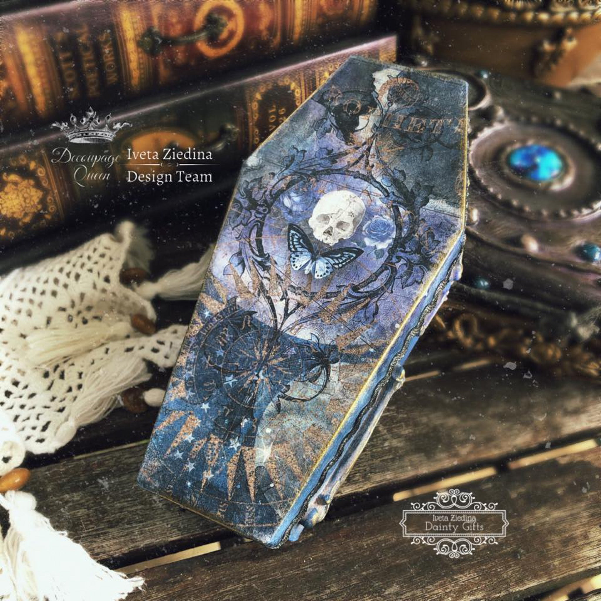 A coffin shaped decoration with the Memento Mori decoupage paper on top. A white Decoupage Queen and Iveta Ziedina Design Team logo on the top left.