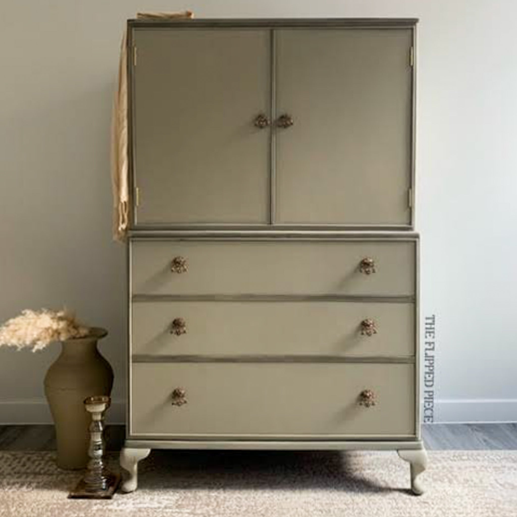 A vintage armoire with 2 doors and 3 drawers refurbished by The Flipped Piece is painted in Dixie Belle's Dried Sage chalk mineral paint.