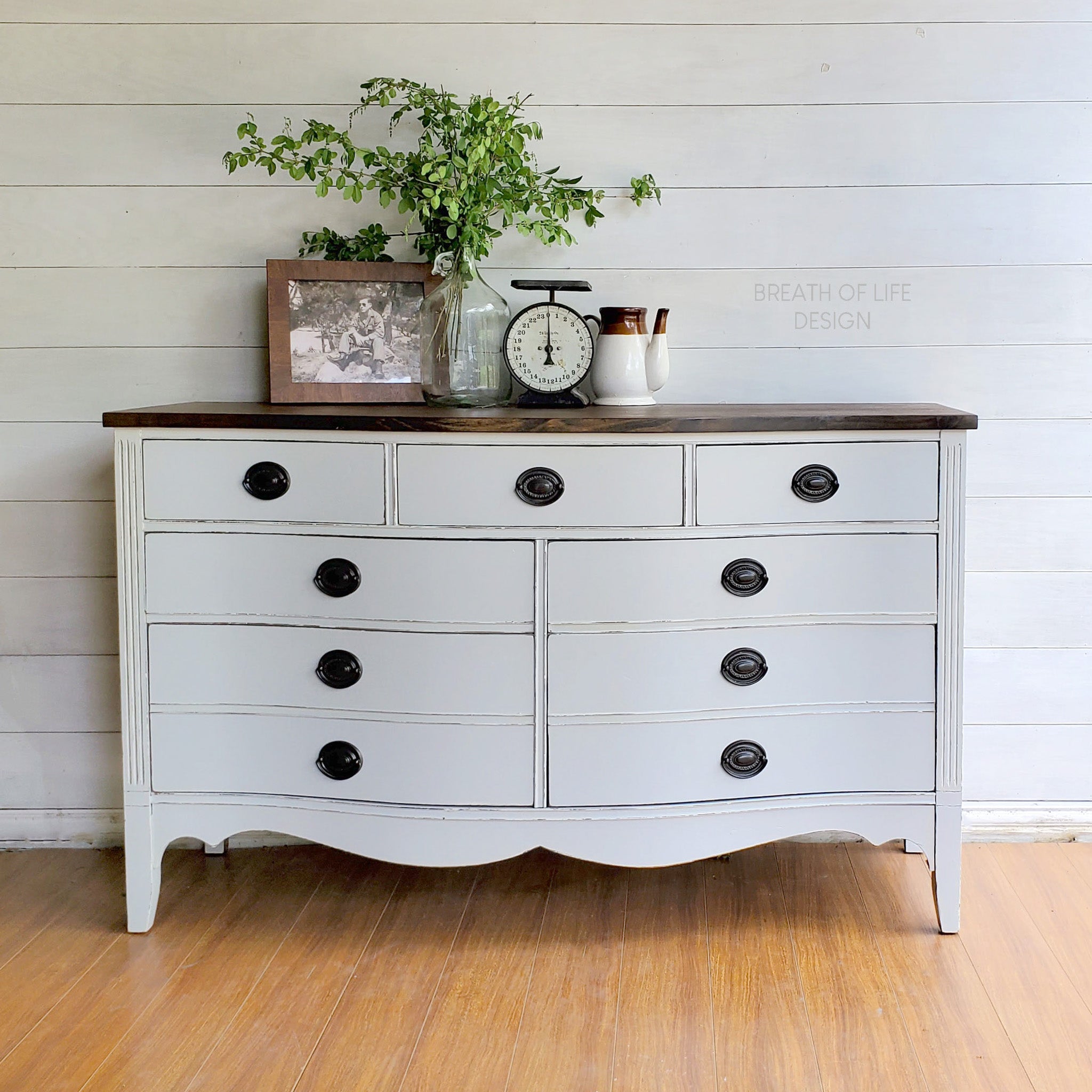 A vintage large dresser refurbished by Breath of Life Design is painted in Dixie Belle's Driftwood chalk mineral paint and has a natural dark wood top on it.