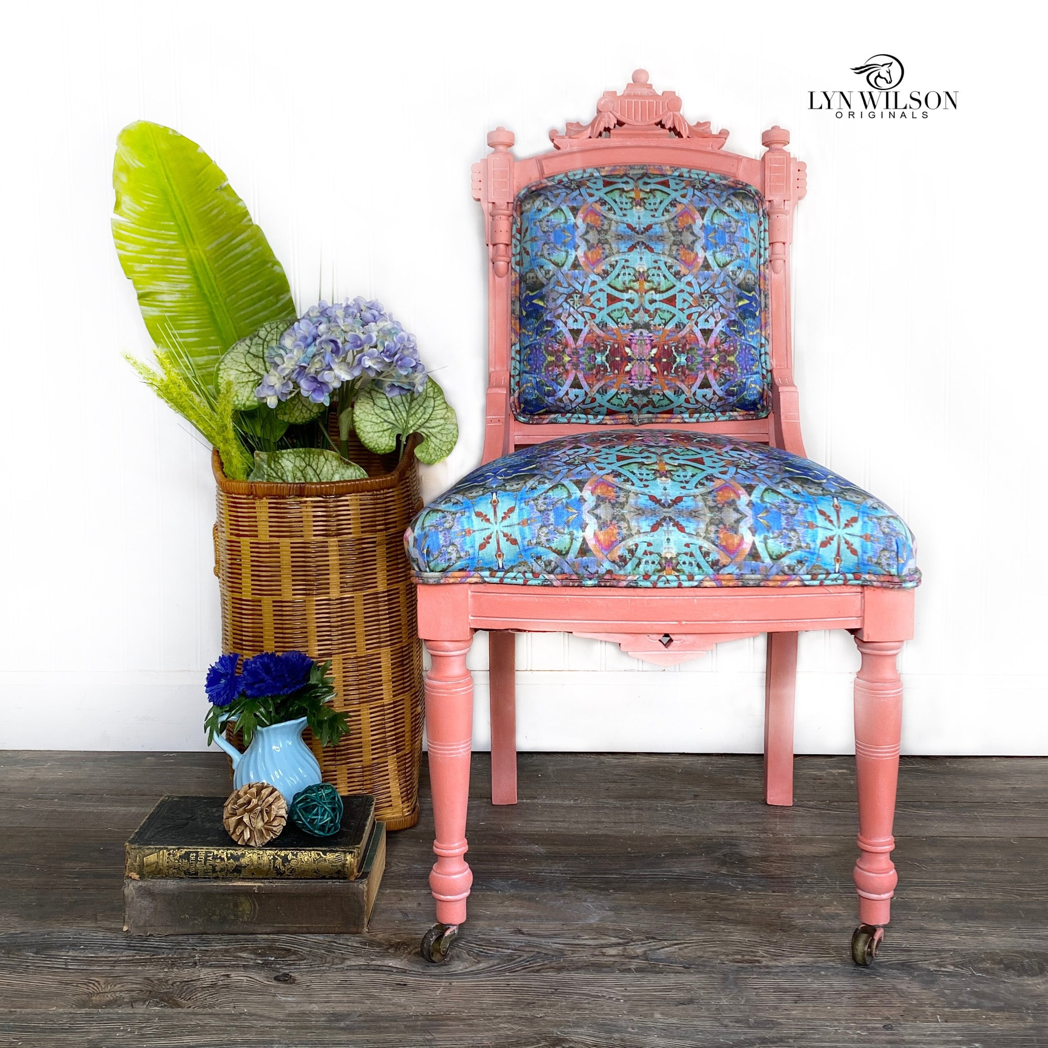 A vintage chair refurbished by Lyn Wilson Originals is painted in Dixie Belle's Flamingo chalk mineral paint and has a light blue patterned material on the seat and back cushion.