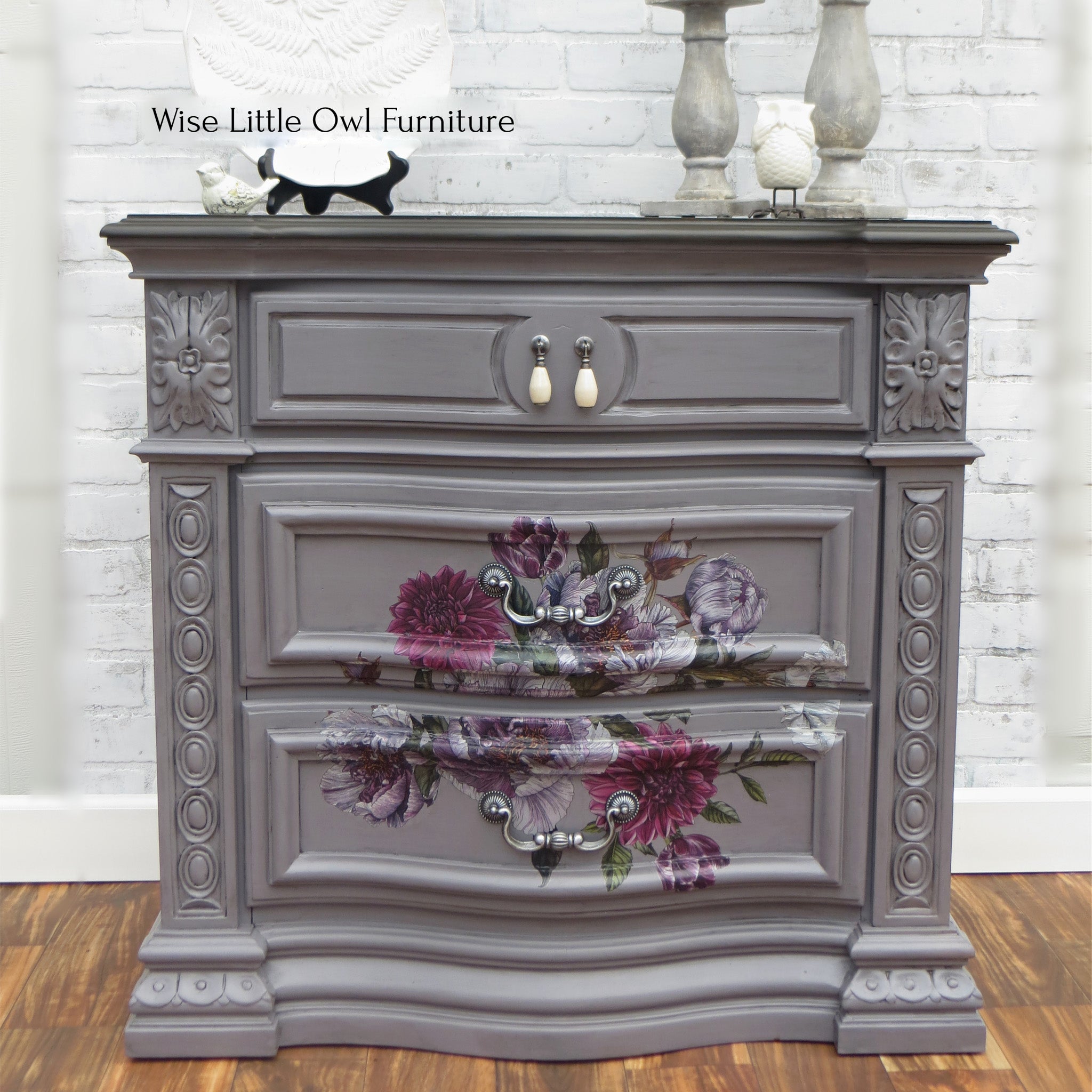 A vintage 3-drawer nightstand refurbished by Wise Little Owl Furniture is painted in Dixie Belle's Mason Dixon chalk mineral paint and has a maroon and lavender floral transfer on the bottom 2 drawers.
