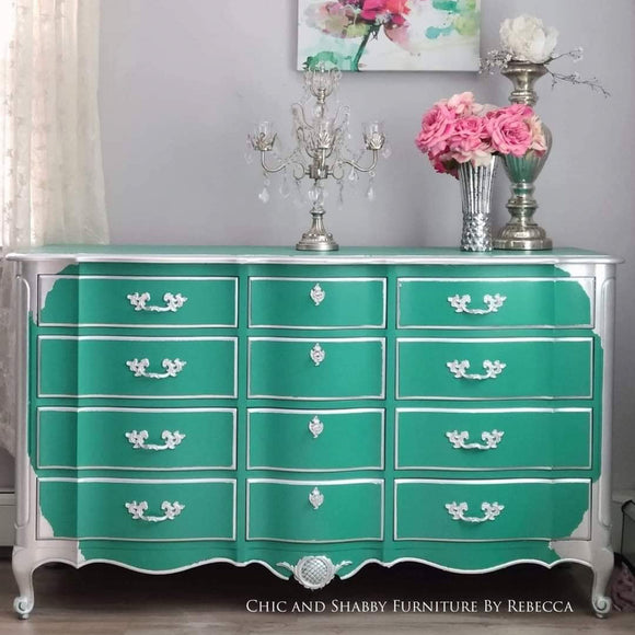 A vintage 12-drawer dresser refurbished by Chic and Shabby Furniture by Rebecca is painted in Dixie Belle's Mermaid Tail chalk mineral paint and has a surrounding framing paint of silver.