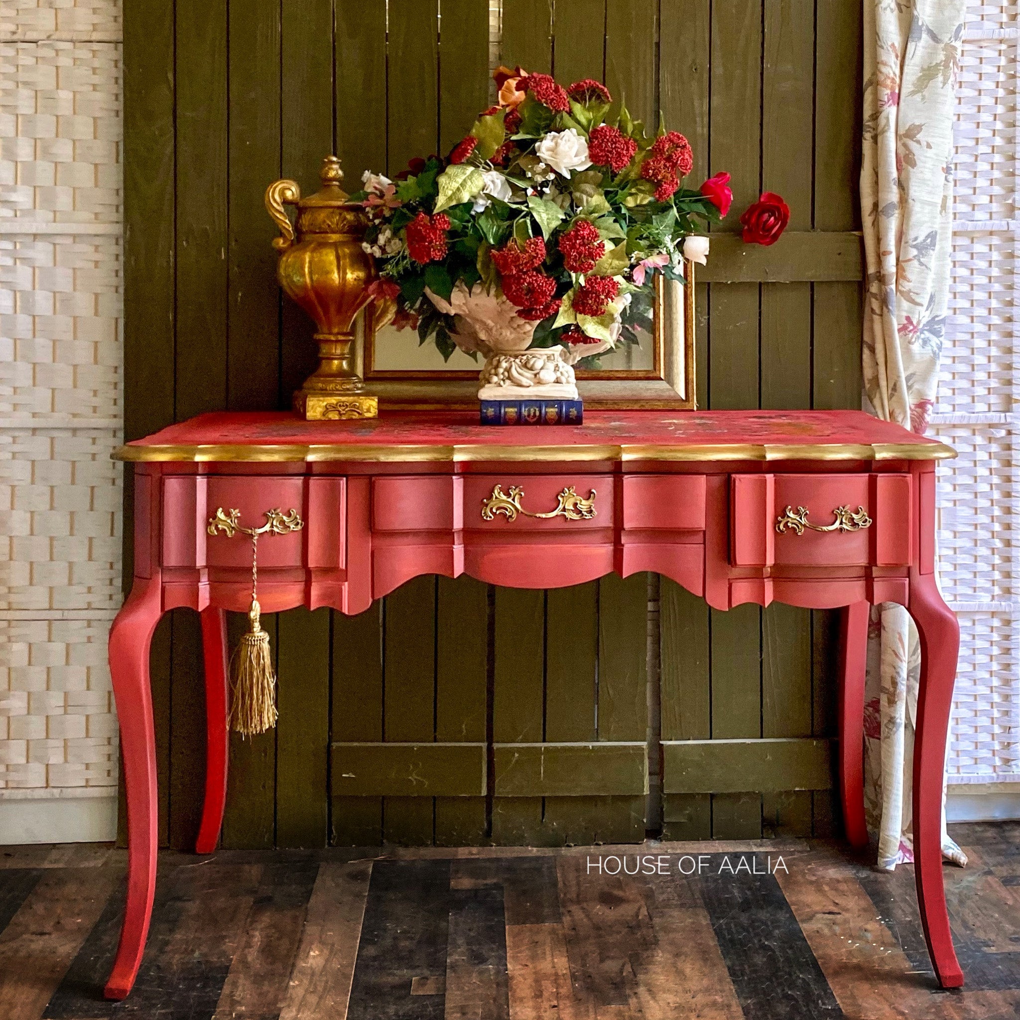 A vintage desk refurbished by House of Aalia is painted in Dixie Belle's Rustic Red and has gold accents.