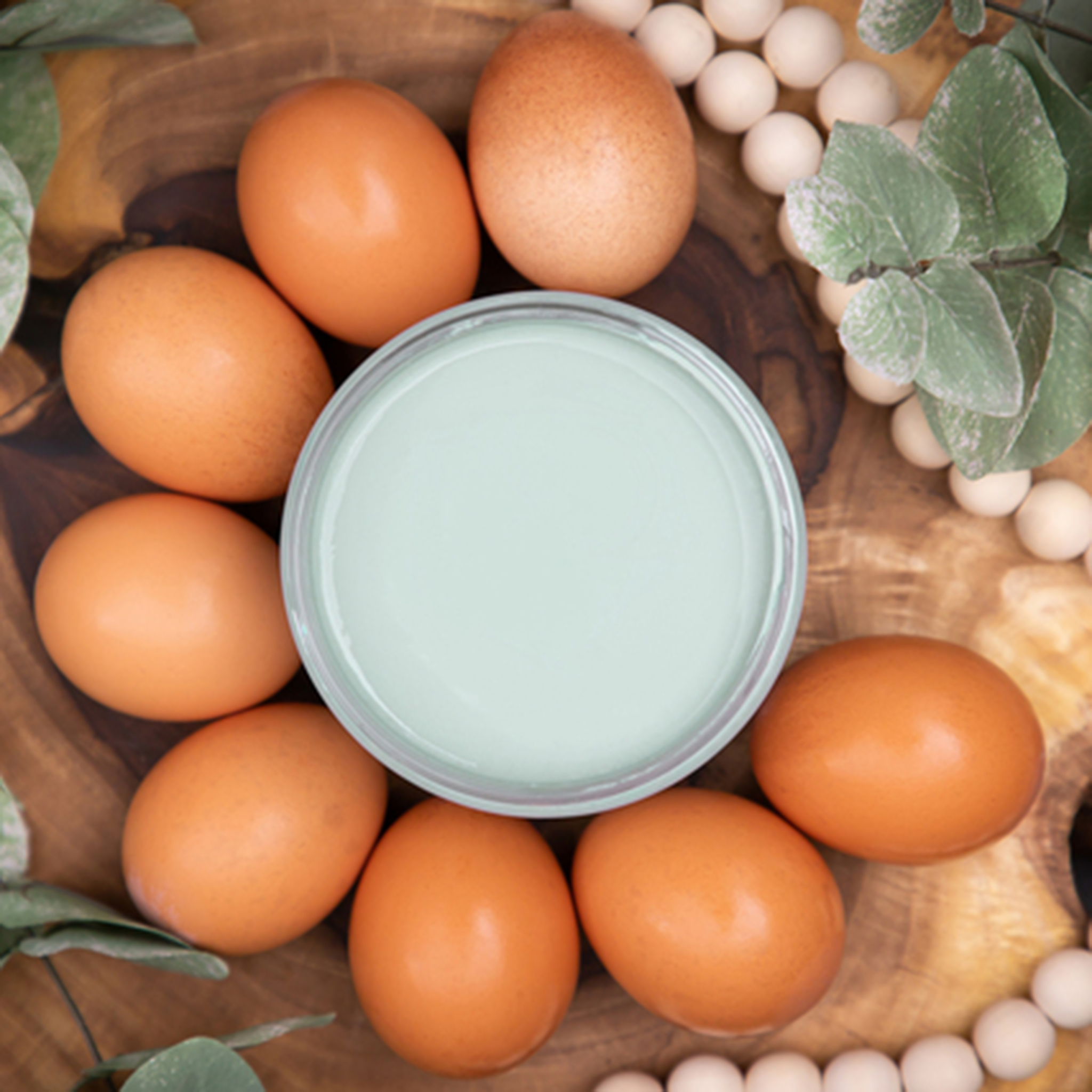 An arial view of an open container of Dixie Belle Paint Company’s Vintage Duck Egg Chalk Mineral Paint is surrounded by brown eggs and wood beads.