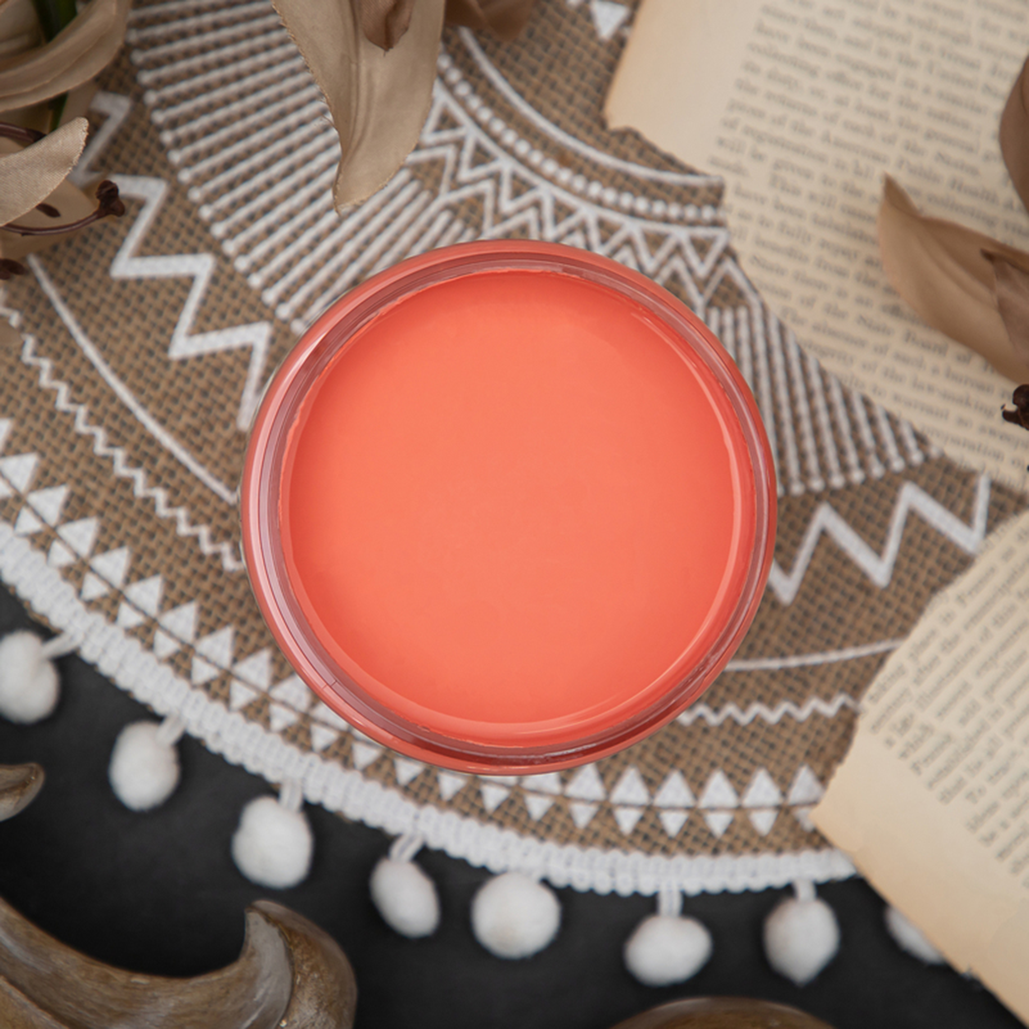An arial view of an open container of Dixie Belle Paint Company’s Flamingo Chalk Mineral Paint is sitting on a round tan mat with different pattern designs on it.