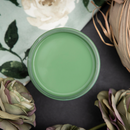 An arial view of an open container of Dixie Belle Paint Company’s Kudzu Chalk Mineral Paint is surrounded by green silk roses