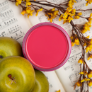 An arial view of an open container of Dixie Belle Paint Company’s Cobblestone Chalk Mineral Paint is sitting on sheet music and surrounded by green apples and yellow flowers.