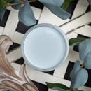 An arial view of an open container of Dixie Belle Paint Company’s Cobblestone Chalk Mineral Paint is against white lattice and eucalyptus leaves.