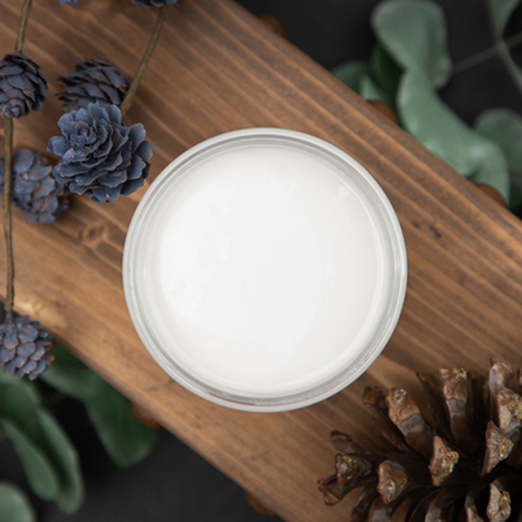 An arial view of an open container of Dixie Belle Paint Company’s Sawmill Gravy Chalk Mineral Paint is on a wood plank and surrounded by pine cones.