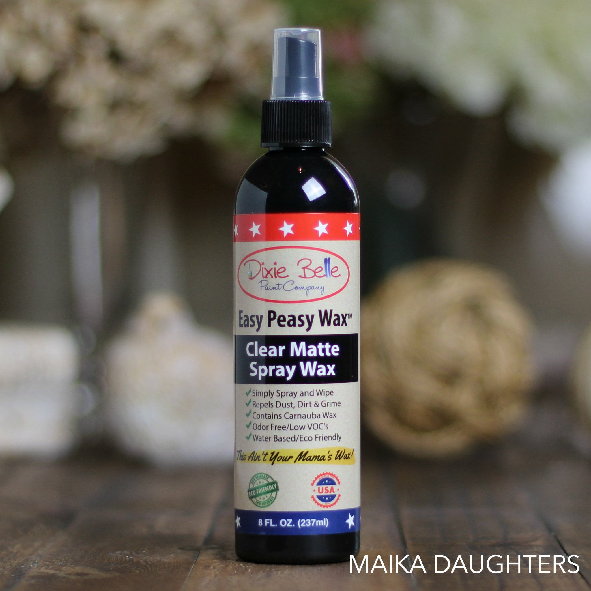 An 8 oz spritz bottle of Dixie Belle's Easy Peasy Wax is sitting on a wood table. 