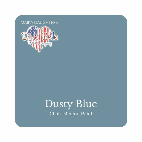 A square swatch card of Dixie Belle Paint Company’s Dusty Blue Chalk Mineral Paint is against a white background. This color is a light blue gray.