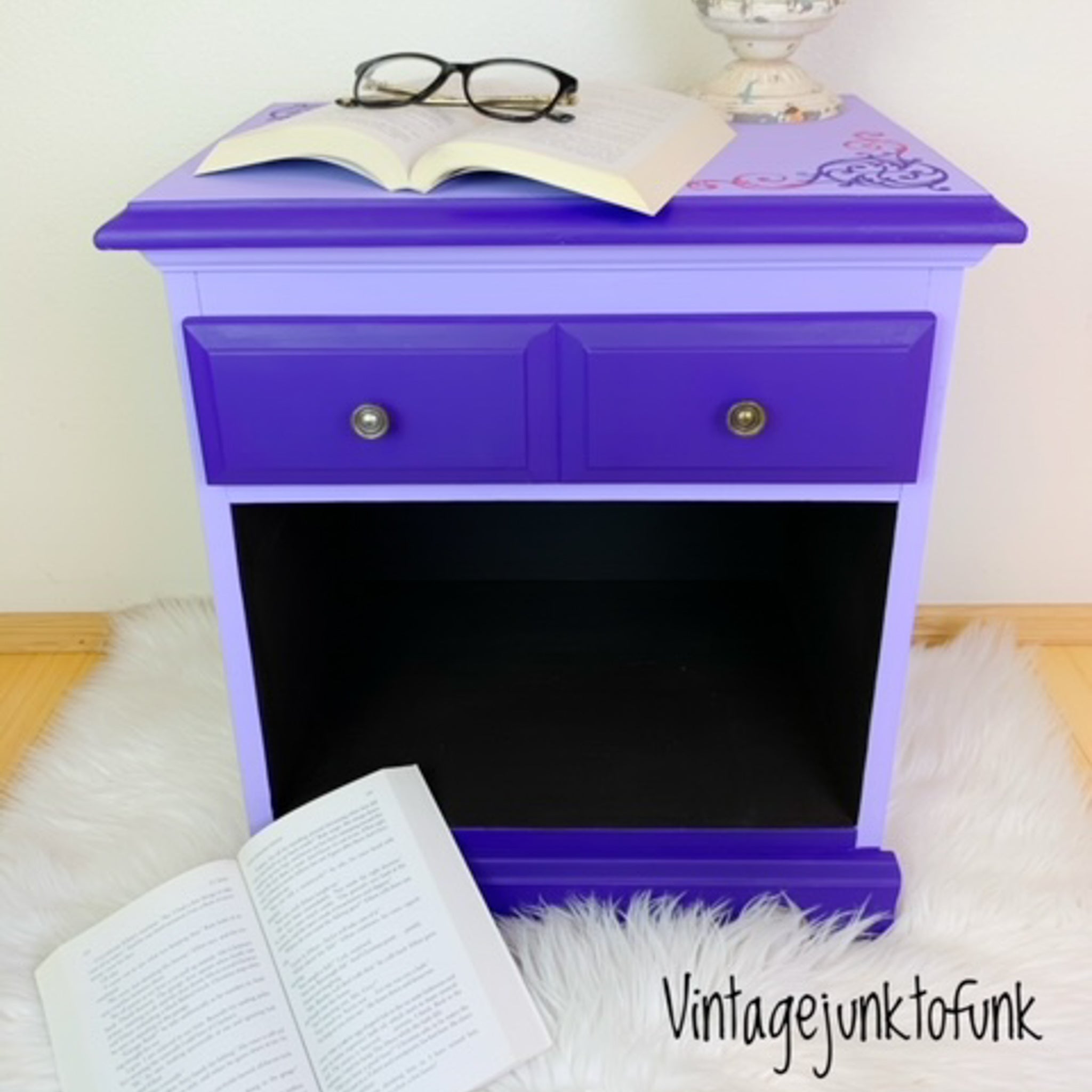 A vintage nightstand with 1 drawer and an open storage cubby refurbished by Vintage Junk to Funk features Dixie Belle's Amethyst Chalk Mineral Paint and a lighter purple color on it.
