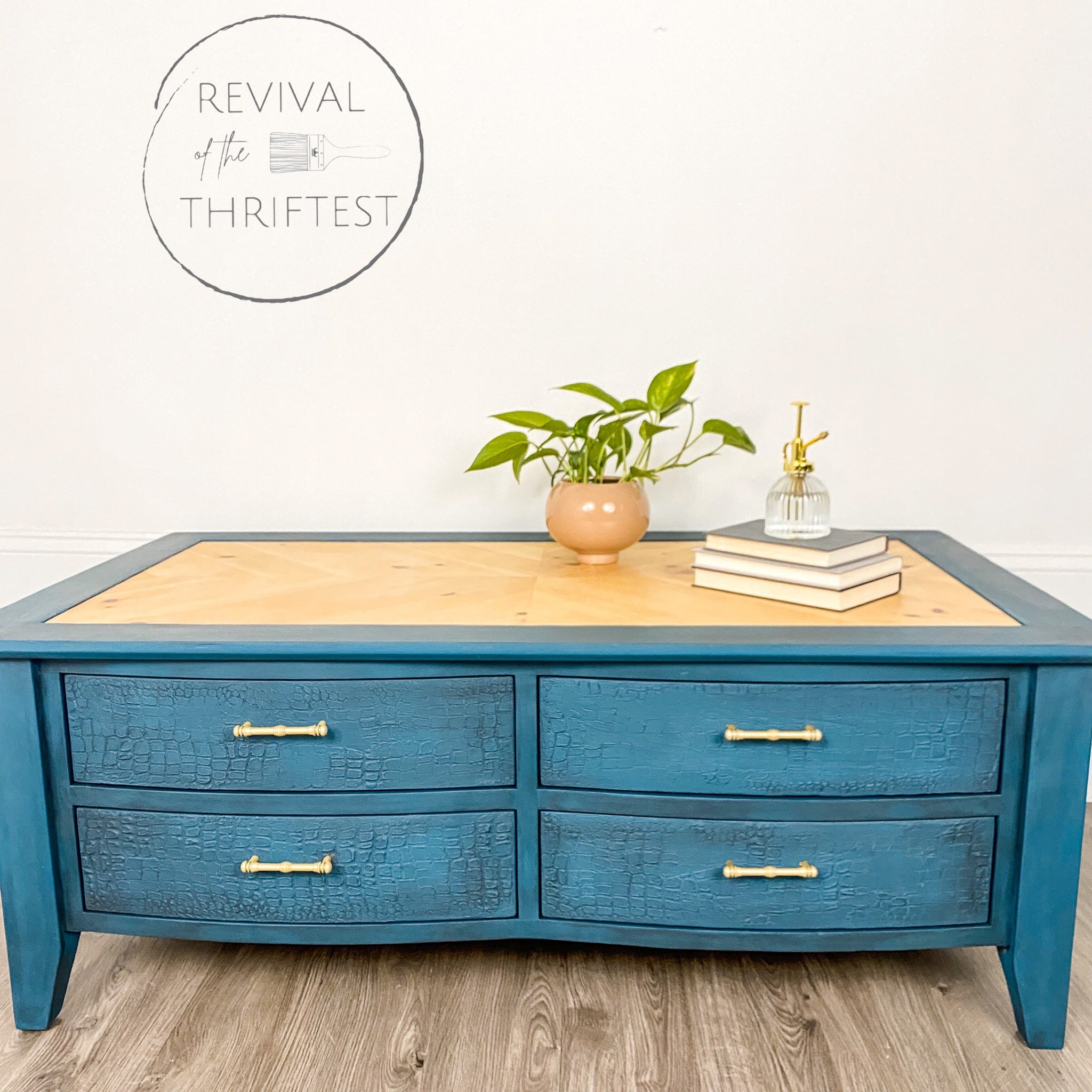 A coffee table with drawers refurbished by Revival of the Thriftest is painted with Dixie Belle's Antebellum Blue chalk mineral paint and has a natural wood table top inlay.