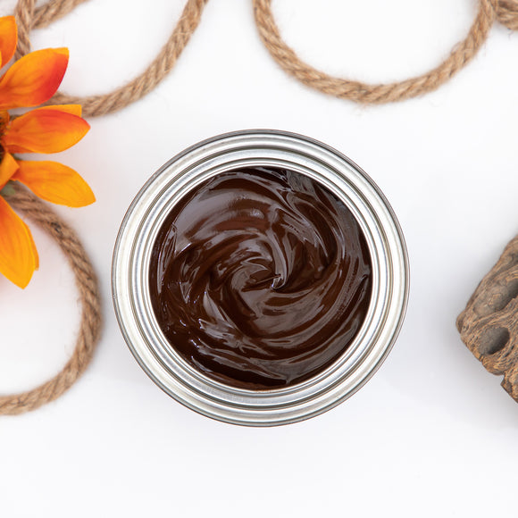 A arial view of an open can of Dixie Belle's No Pain Gel Stain is against a white background. To the left and above the can is rope with an orange silk flower and to the right is a piece of driftwood.