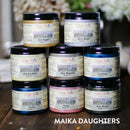 8  Moonshine Metallic paints: Gold Digger, Silver Bullet, Wedding Belle, Steel Magnolia, Caribbean, Pacific, Rozay, and Deep woods. A white Maika Daughters logo on the bottom right.