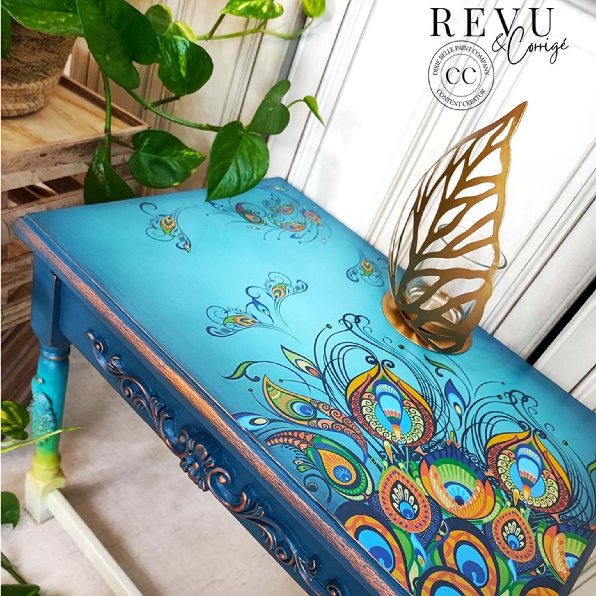 A vintage table refurbished by Revu & Corrigé, a Dixie Belle Paint Company Content Creator, is painted a blend of bright blues and features the Retro Peacock transfer on the top.