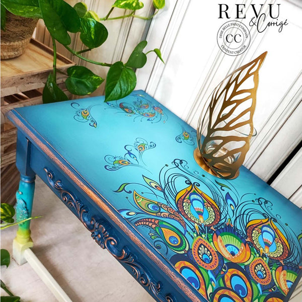 A vintage table refurbished by Revu & Corrigé, a Dixie Belle Paint Company Content Creator, is painted a blend of bright blues and features the Retro Peacock transfer on the top.