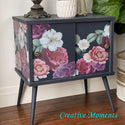 A vintage side table with 2 sliding doors refurbished by Creative Moments is painted a soft, dark blue and features the Floral Romance transfer.