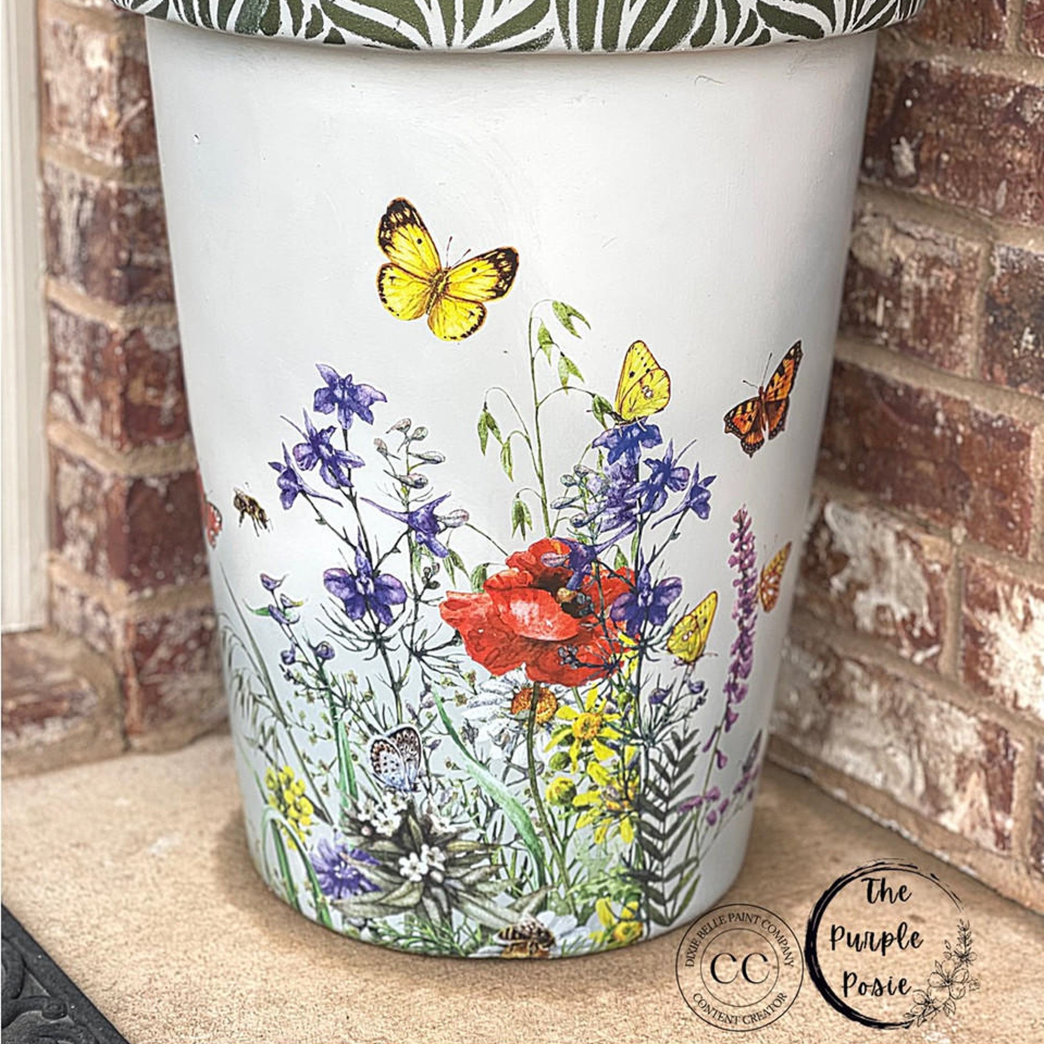 Close-up of a vintage side drum table refurbished by The Purple Posie, a Dixie Belle Paint Company Content Creator, is painted white and features the Wildflowers & Butterflies Transfer on it.