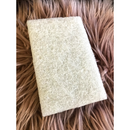 A rectangular white finishing pad is sitting on a mauve colored, long, faux fur piece of carpet.