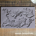 Baroque Swirls mold tray on a wooden background. A white Maika Daughters logo on the bottom right.