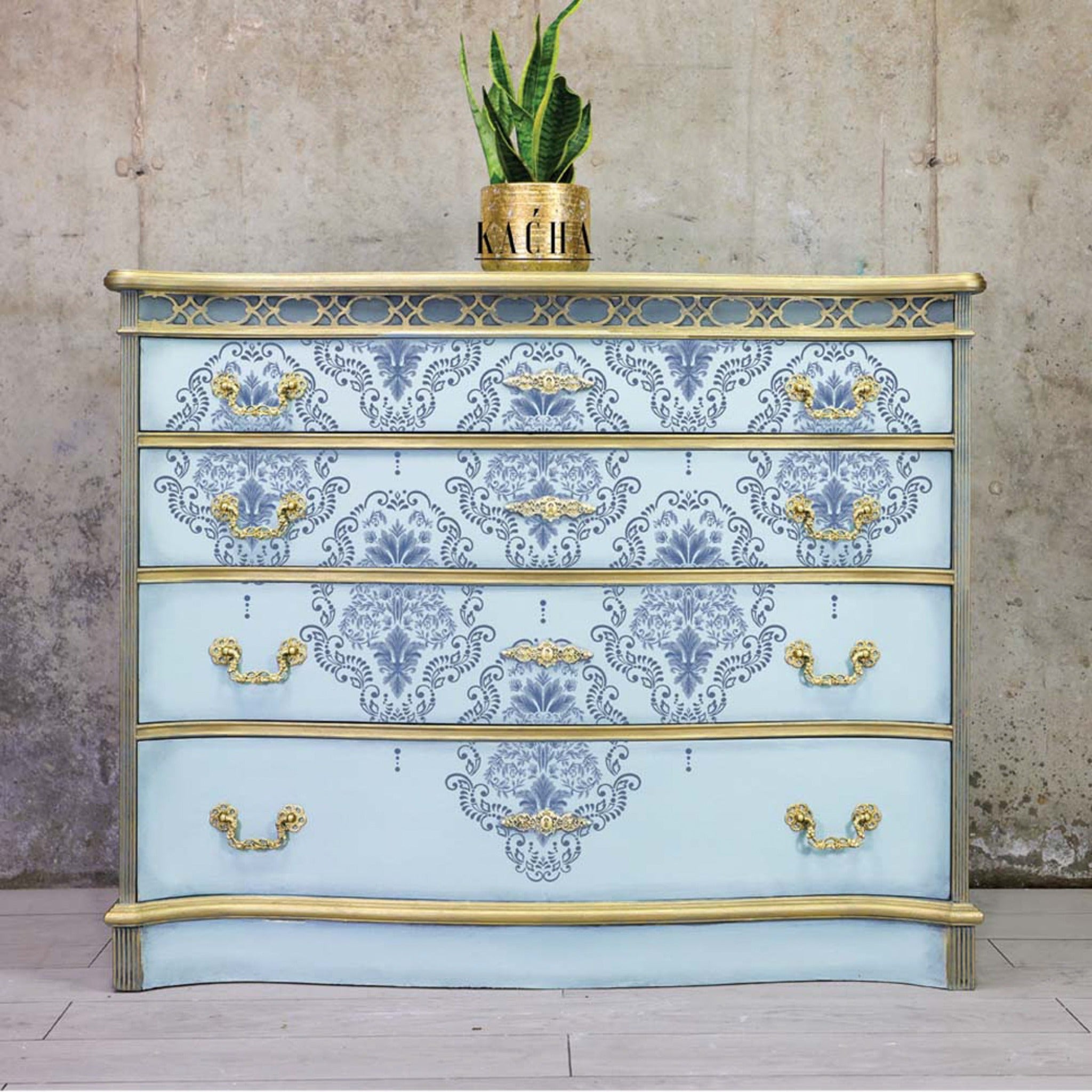 A 4-drawer dresser refurbished by Kacha is painted light blue with gold accents and features the Kacha Dana Damask transfer on it.