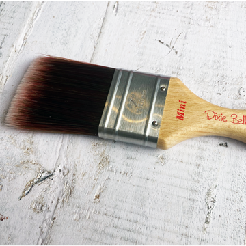 Dixie Belle Paint Company's Mini Synthetic Paint Brush is against a white wood background.