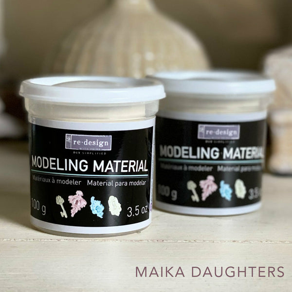 Two air dry modeling material containers reading: Redesign with prima. Modeling Material. Materiaux a modeler. Material para modelar. 100 g. 3.5 oz. A mauve Maika Daughters logo on the bottom right.