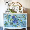 A vintage dresser refurbished by New Old Finds is painted white with blue drawers and features the Cosmic Roses transfer on it.