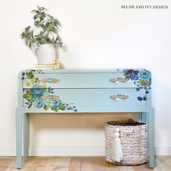 A vintage side table refurbished by Blush and Ivy Design is painted light blue and features the Cosmic Roses transfer on it.