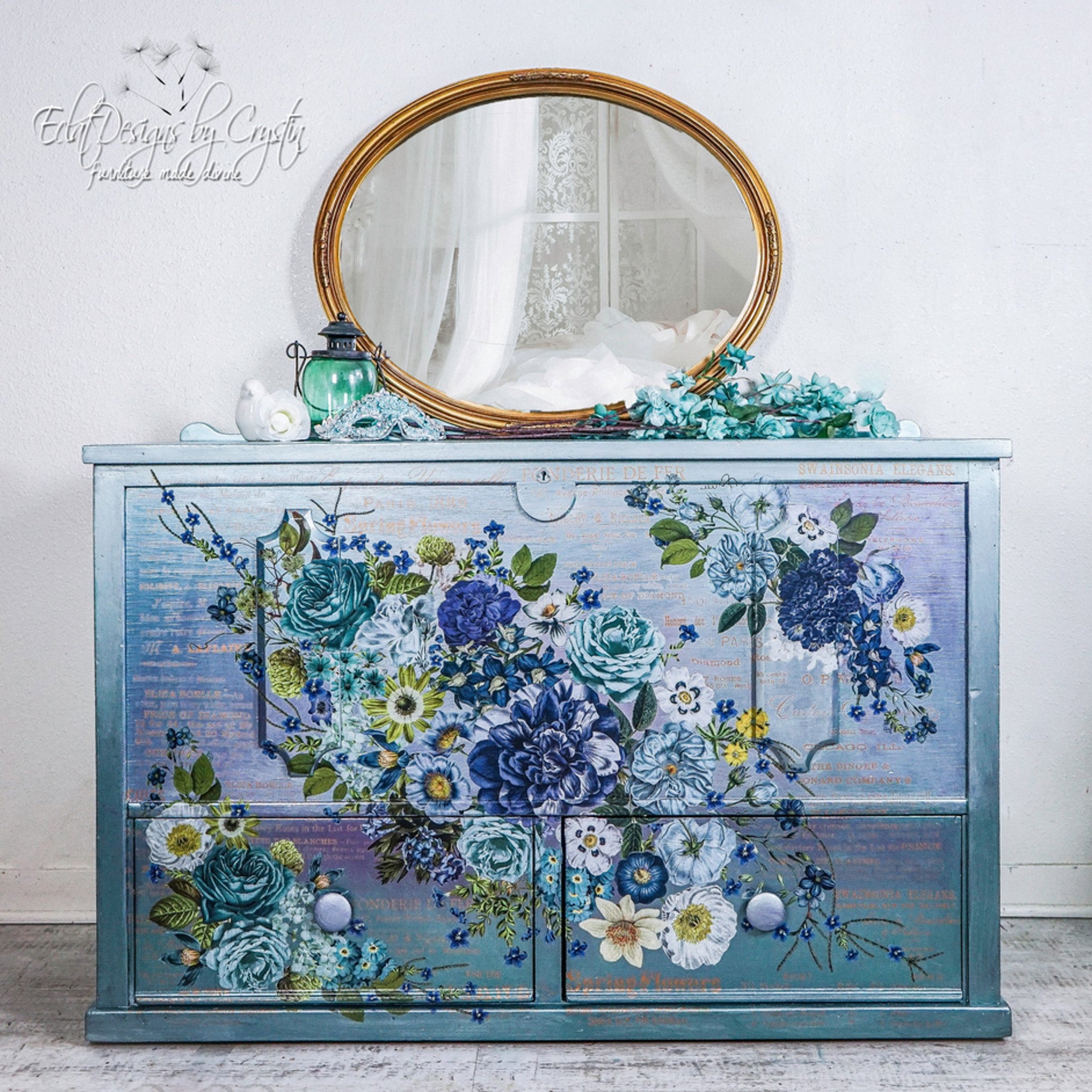 A vintage dresser refurbished by Eclat Designs by Crystin is painted a blend of blues and features the Cosmic Roses transfer on its drawers.