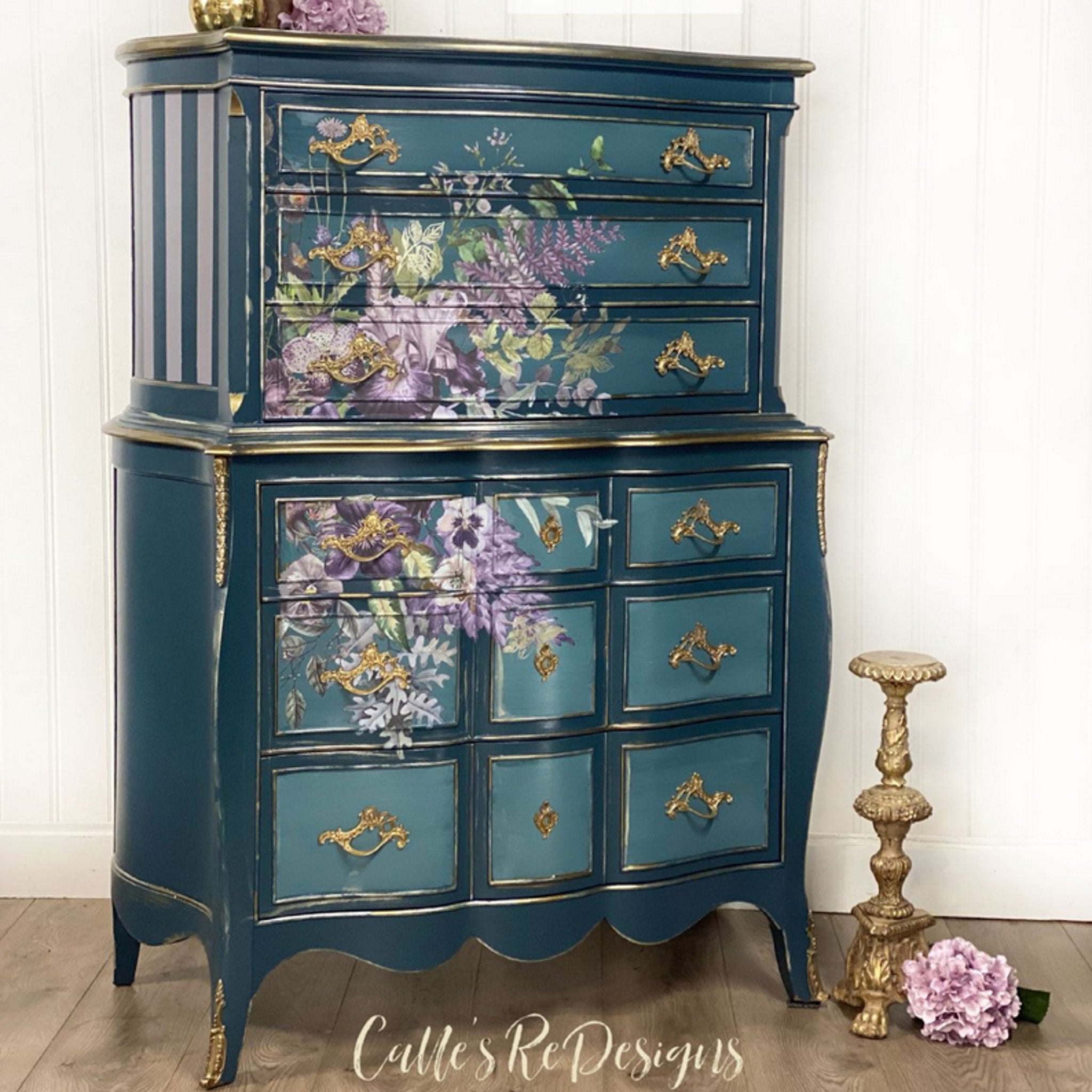 A vintage lingerie dresser refurbished by Calle's ReDesigns is painted blue with gold accents and features ReDesign with Prima's Vigorous Violet transfer on it.