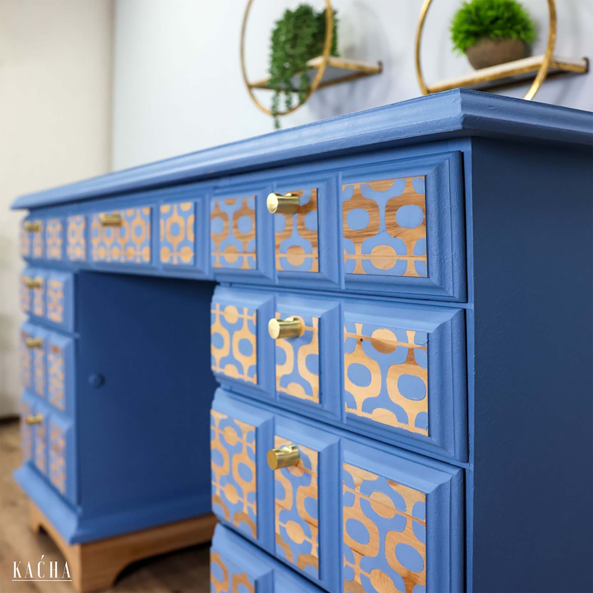 A vintage desk refurbished by Kacha is painted blue and features ReDesign with Prima's Midcentury Vibes stencil in gold on its drawers.