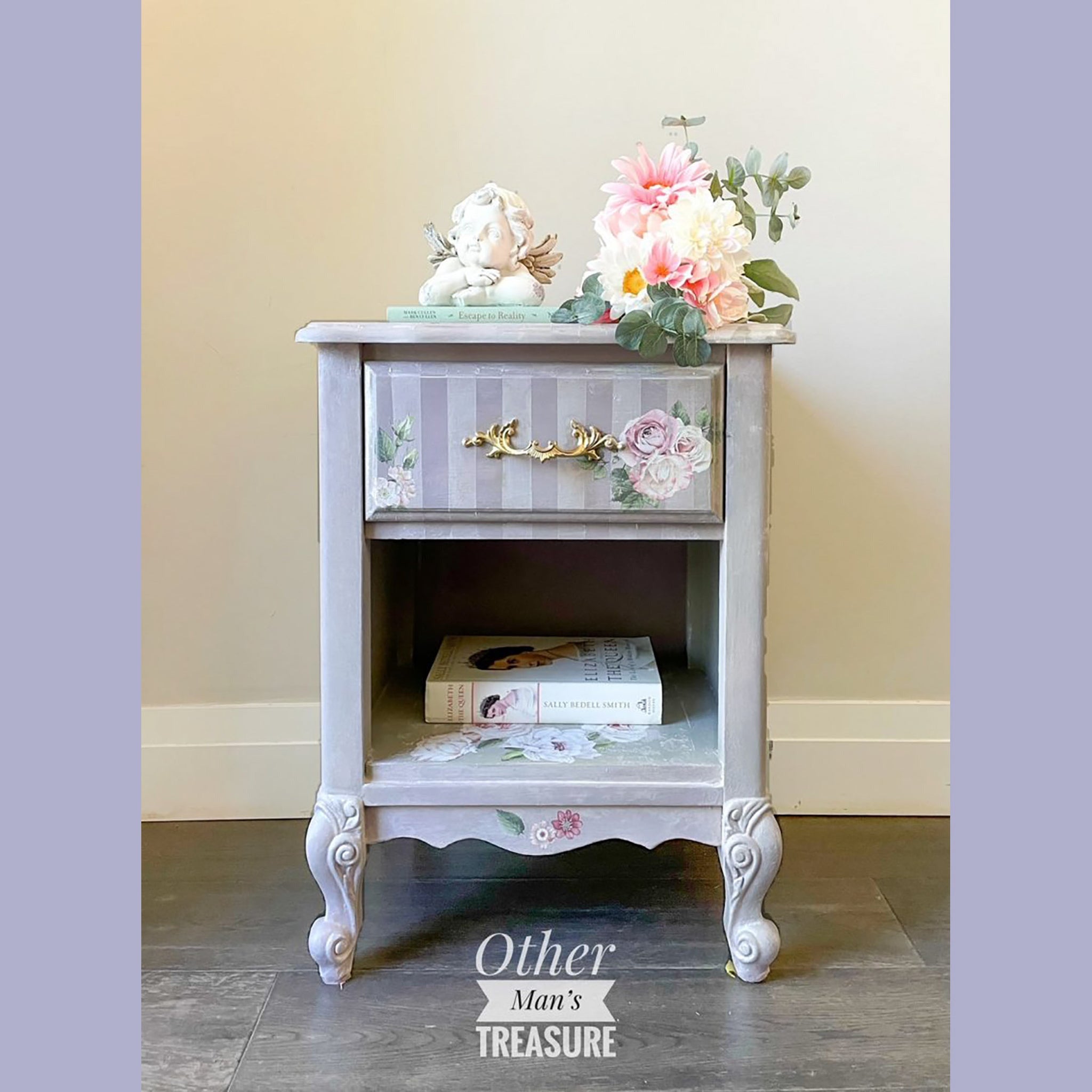 A vintage nightstand with 1 drawer and an open bottom shelf refurbished by Other Man's Treasure is painted light greyand features the Delicare Roses small transfer on it.