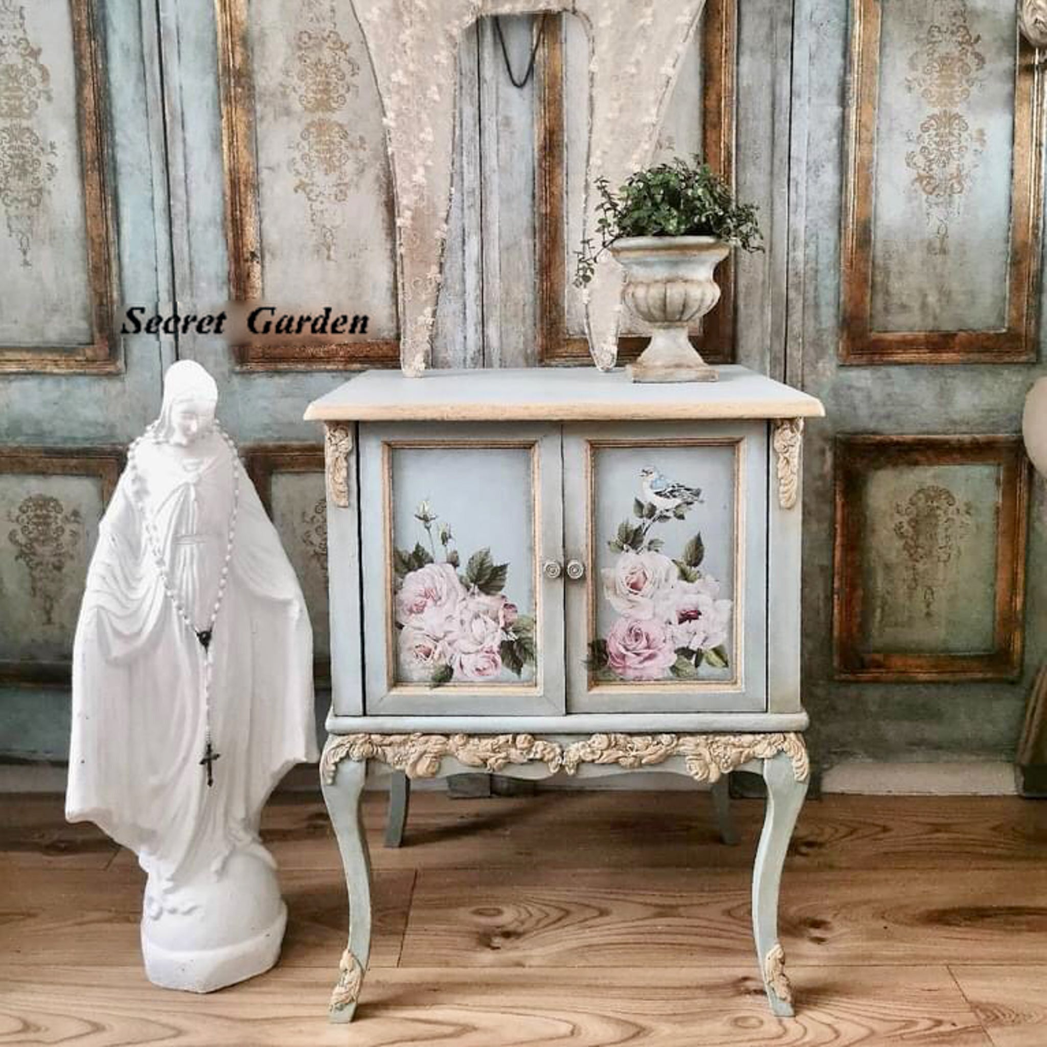 A vintage 2-door nightstand refurbished by Secret Garden is painted a blend of pale blue and tan and features the Delicate Roses small transfer on the doors.