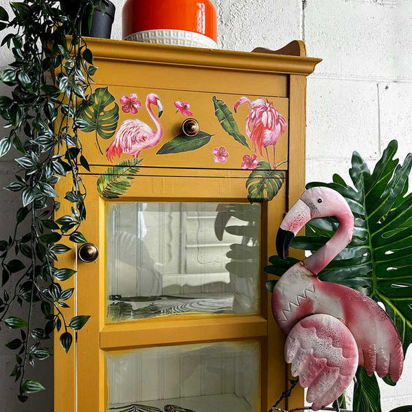 A wood curio cabinet is painted an amber orange and features the Flaimgo Pink small transfer on it.
