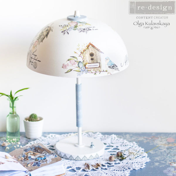 A lamp shade refurbished by Olga Kulavskaya is painted white and features the Garden Marvels small transfer on it.